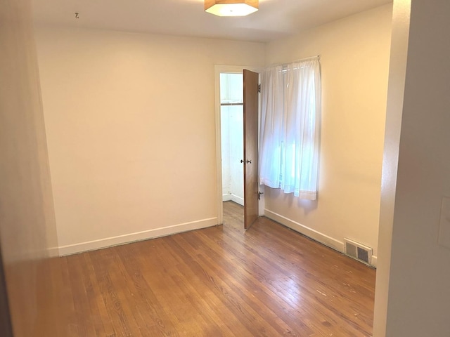 spare room with visible vents, baseboards, and wood finished floors