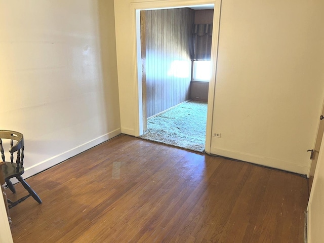 spare room featuring baseboards and wood finished floors