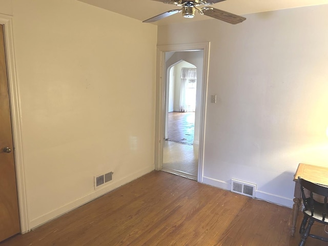 spare room with a ceiling fan, visible vents, baseboards, and wood finished floors