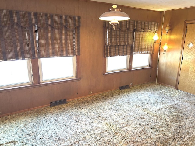 unfurnished room featuring wood walls, carpet, and visible vents