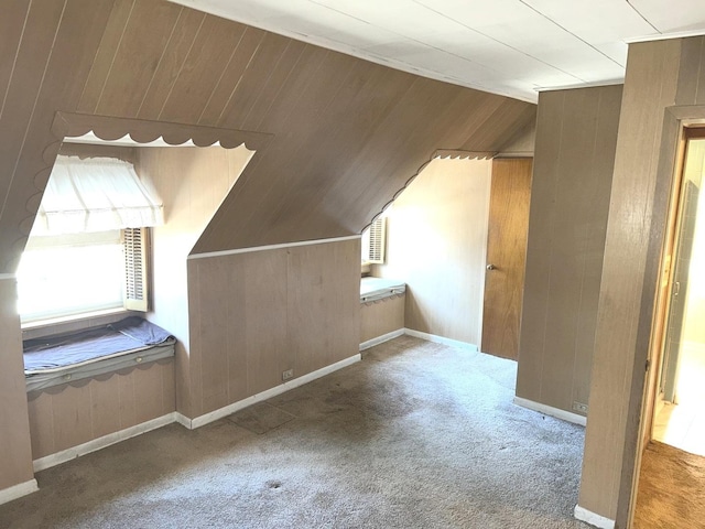 bonus room featuring carpet, vaulted ceiling, wooden walls, and baseboards