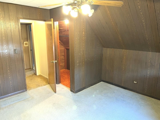 bonus room featuring carpet, vaulted ceiling, wood walls, and ceiling fan