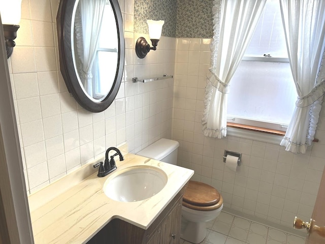 bathroom featuring toilet, tile walls, and vanity