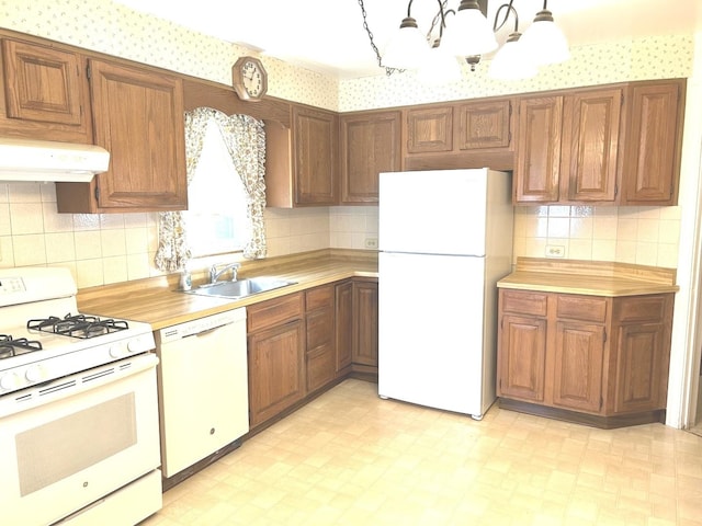 kitchen with white appliances, under cabinet range hood, light floors, and a sink