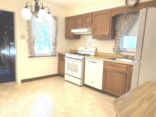 kitchen with white appliances, light countertops, a sink, and under cabinet range hood