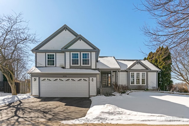 view of front facade with an attached garage, fence, and aphalt driveway