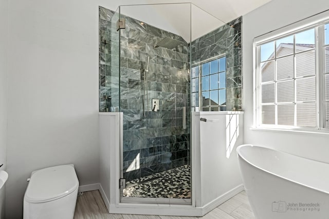 full bath featuring a stall shower, baseboards, a freestanding bath, and toilet