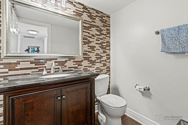 bathroom with visible vents, toilet, decorative backsplash, vanity, and baseboards