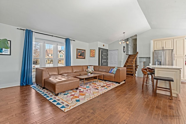 living room with a chandelier, stairway, dark wood-style floors, and lofted ceiling