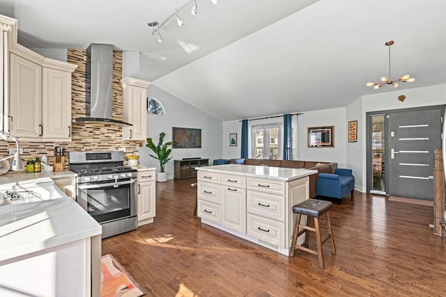 kitchen with open floor plan, light countertops, wall chimney range hood, and stainless steel gas range oven