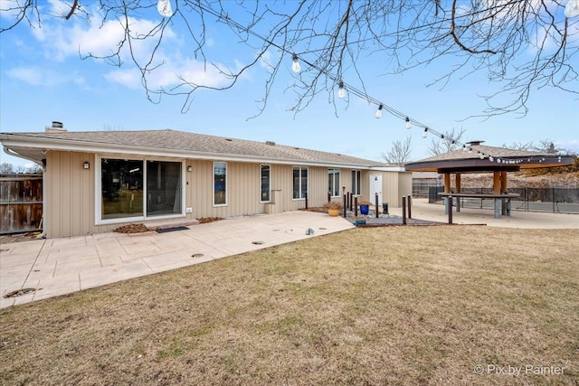 rear view of house with a yard, a chimney, a gazebo, a patio, and fence