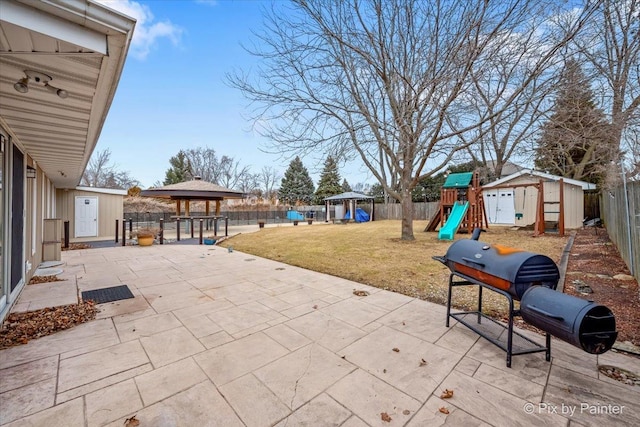 view of patio featuring a gazebo, an outdoor structure, a shed, a fenced backyard, and a playground