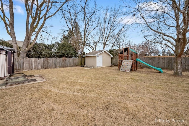 view of yard with a storage unit, an outdoor structure, a playground, and a fenced backyard