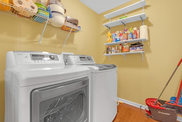 clothes washing area featuring independent washer and dryer and light hardwood / wood-style floors