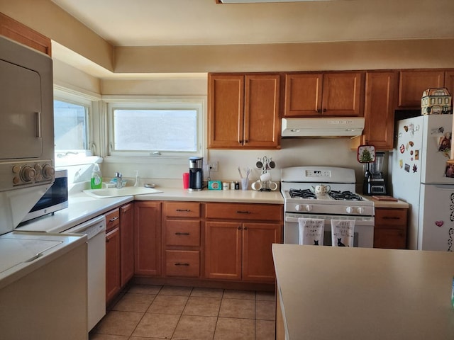 kitchen featuring sink, white appliances, light tile patterned floors, and stacked washing maching and dryer