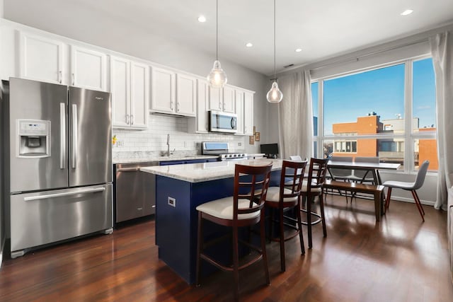 kitchen featuring white cabinets, appliances with stainless steel finishes, pendant lighting, and a kitchen island