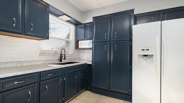 kitchen with tasteful backsplash, sink, light tile patterned floors, blue cabinetry, and white appliances