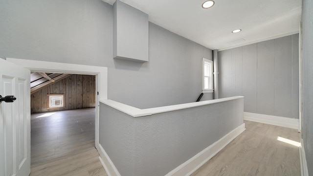 hallway with light wood-type flooring and wood walls