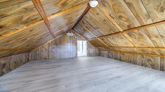 additional living space featuring lofted ceiling, hardwood / wood-style flooring, and wood walls