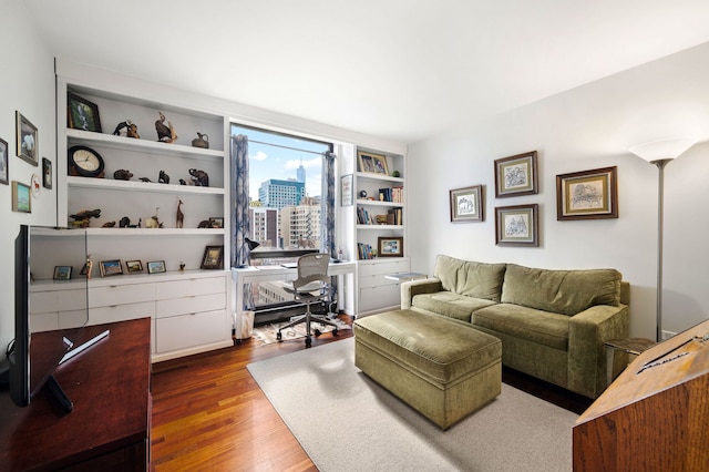 living room with dark wood-type flooring, a view of city, and built in shelves