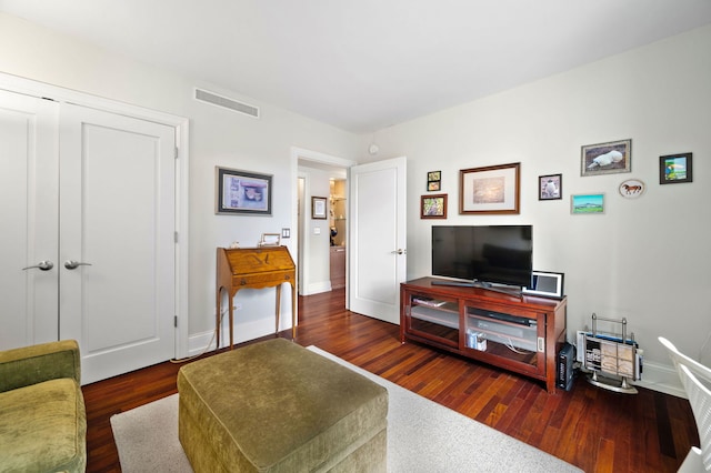 living area with baseboards, visible vents, and wood finished floors