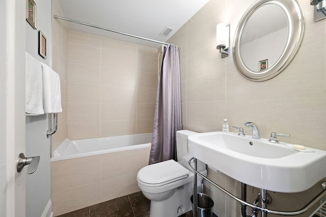 full bath with toilet, tiled shower / bath, visible vents, and tile walls