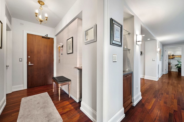 entryway featuring a notable chandelier, baseboards, and dark wood-style flooring