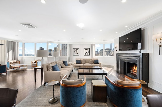 living area featuring visible vents, a decorative wall, a wealth of natural light, and wood finished floors