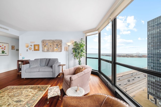 living area featuring a water view, wood finished floors, visible vents, and floor to ceiling windows