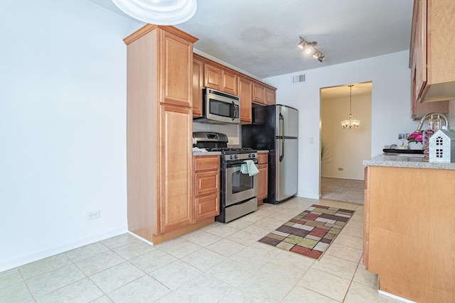 kitchen featuring appliances with stainless steel finishes, sink, a chandelier, light tile patterned floors, and decorative light fixtures