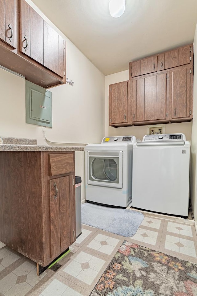 clothes washing area with washer and dryer, cabinets, and electric panel