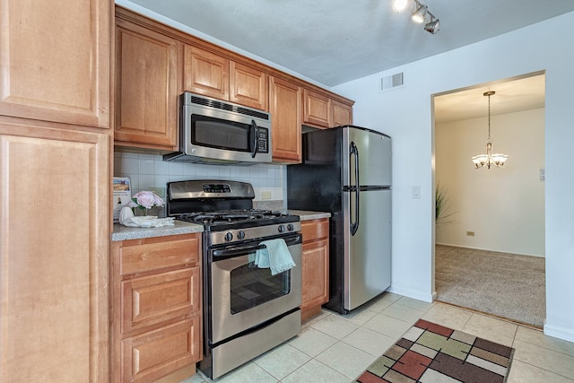 kitchen with decorative light fixtures, a notable chandelier, light tile patterned floors, appliances with stainless steel finishes, and decorative backsplash