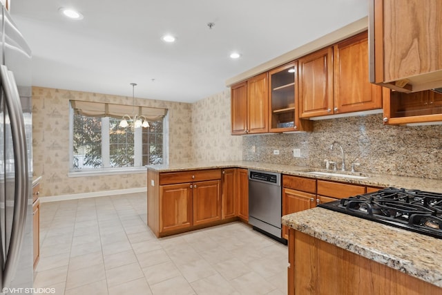 kitchen featuring appliances with stainless steel finishes, sink, hanging light fixtures, light stone counters, and kitchen peninsula