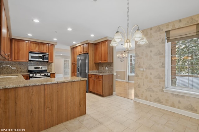 kitchen featuring sink, a chandelier, hanging light fixtures, kitchen peninsula, and stainless steel appliances