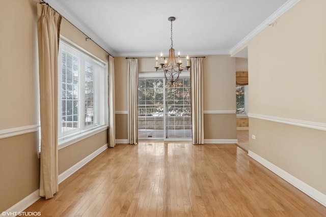 unfurnished dining area with an inviting chandelier, ornamental molding, and light wood-type flooring