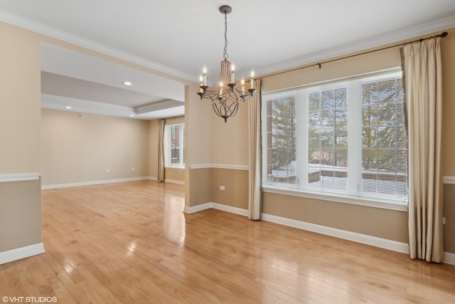 unfurnished dining area featuring ornamental molding, a notable chandelier, light hardwood / wood-style floors, and a tray ceiling