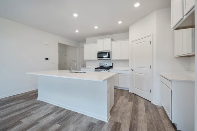 kitchen with an island with sink, white cabinetry, stainless steel appliances, and sink