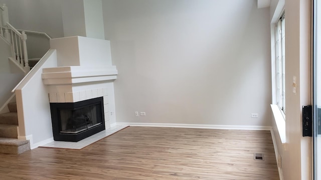 unfurnished living room with a tile fireplace and light wood-type flooring