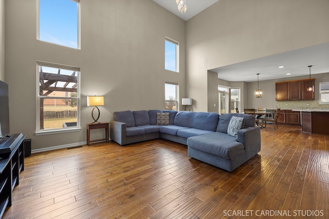 living room with baseboards, dark wood-type flooring, visible vents, and an inviting chandelier