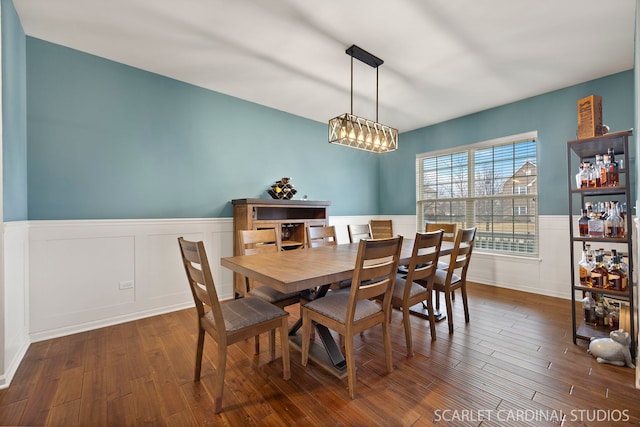 dining room with a wainscoted wall, a chandelier, and wood finished floors