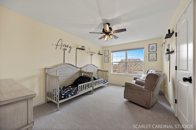 carpeted bedroom featuring a ceiling fan, a nursery area, and baseboards