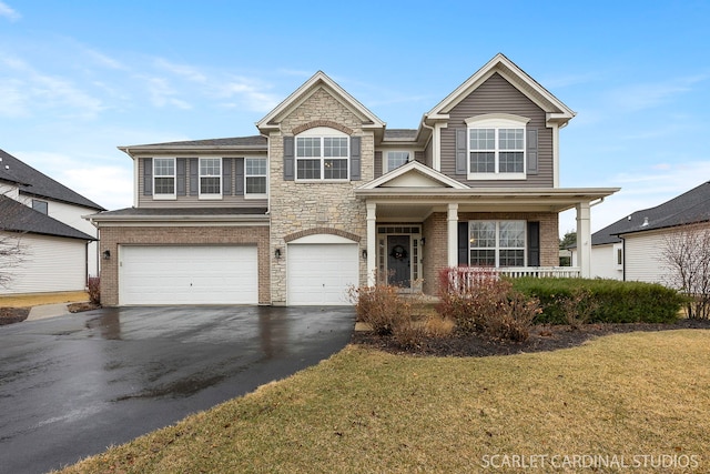 traditional-style home featuring driveway, a garage, stone siding, a porch, and a front lawn