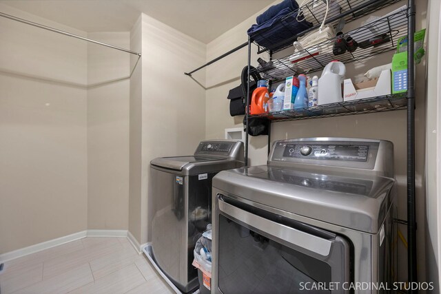 washroom with tile patterned flooring, laundry area, baseboards, and separate washer and dryer