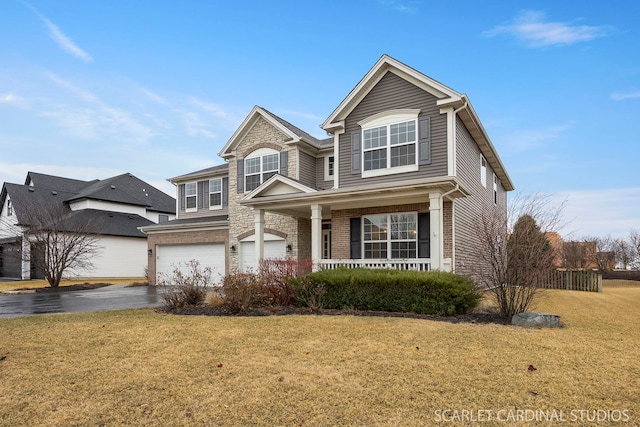 traditional-style home featuring a garage, driveway, a front yard, a porch, and brick siding