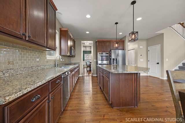 kitchen featuring appliances with stainless steel finishes, a center island, a sink, and dark wood-style floors