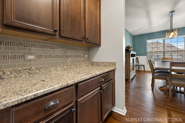 kitchen with dark wood finished floors, backsplash, dark brown cabinets, and light stone countertops