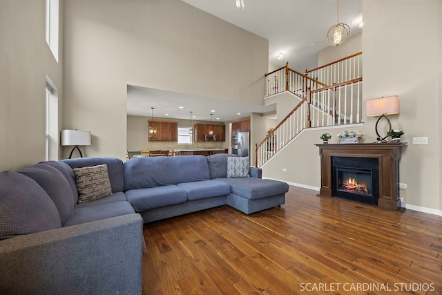 living room featuring dark wood-style flooring, plenty of natural light, and stairs