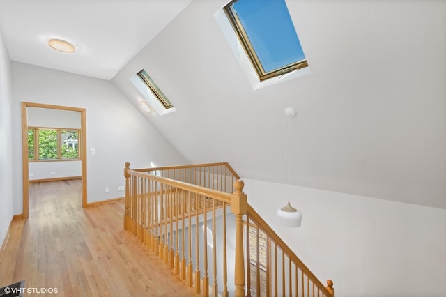 corridor with lofted ceiling with skylight and light wood-type flooring