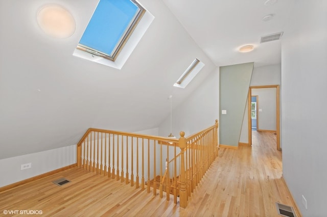 hall featuring lofted ceiling with skylight and light hardwood / wood-style floors