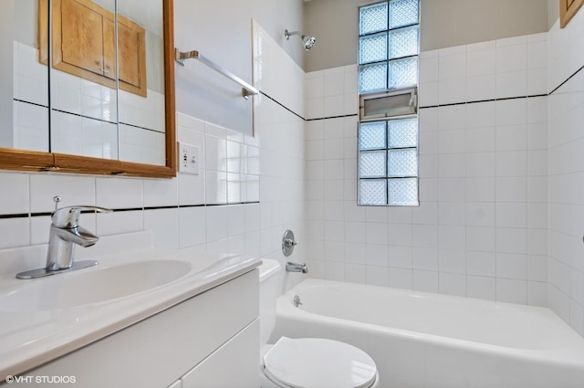 full bathroom featuring toilet, tile walls, vanity, tiled shower / bath combo, and backsplash